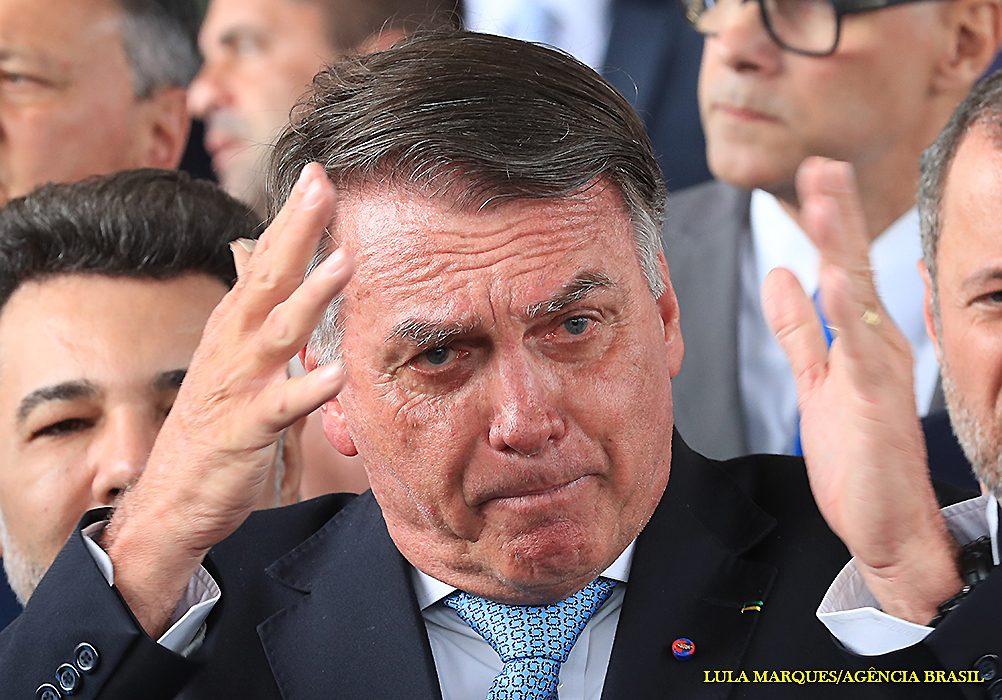 O ministro Alexandre de Moraes, do STF, decretou prisão domiciliar para Jair Bolsonaro nesta segunda-feira (4), acompanhada de busca e apreensão e novas restrições severas. A medida veio após o descumprimento de cautelares, incluindo a proibição de uso de redes sociais de terceiros. Flávio Bolsonaro publicou um vídeo do ex-presidente, ignorando as restrições. Os advogados de Bolsonaro souberam da decisão pela imprensa enquanto a PF agia. Moraes justificou a decisão citando o incentivo a ataques ao STF e apoio a intervenção estrangeira, no âmbito de um inquérito que investiga Eduardo Bolsonaro e a trama golpista.